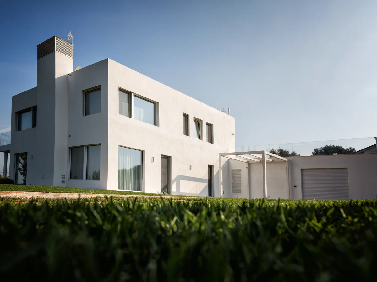 Villa moderna in bianco con ampie finestre a filo muro, vista dal giardino