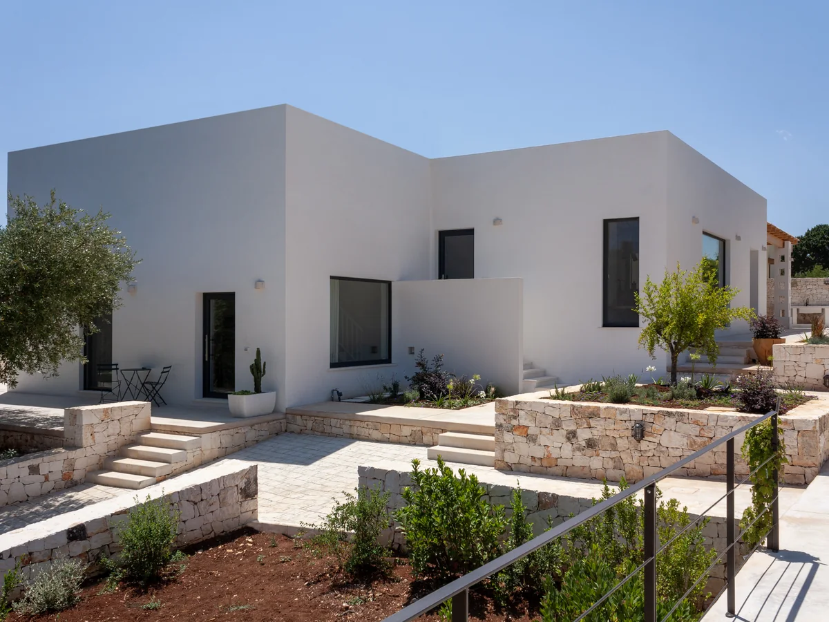 Villa contemporanea con serramenti scuri, muretti a secco e giardino mediterraneo